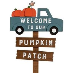 a wooden sign that says welcome to our pumpkin patch and two pumpkins on top