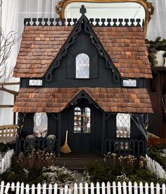 a doll house is shown in front of a mirror and window with a white picket fence