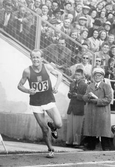 an old photo of a man running in front of a crowd