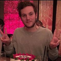 a man sitting at a table with a cake in front of him that has candles on it