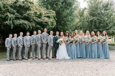 a large group of people standing next to each other in front of trees and bushes