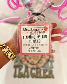 a teacher appreciation card being held up by someone's hand with pink ribbon around it