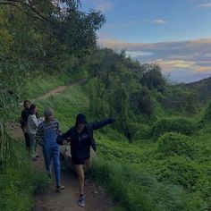 three people walking up a hill on a trail