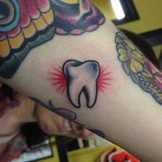 a person with a tattoo on their arm has a tooth in the middle of it