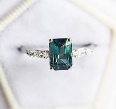 an emerald colored ring with two white diamonds