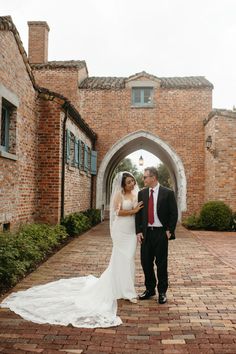 a bride and groom standing in front of an archway