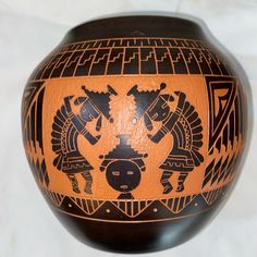 an orange and black vase with designs on it