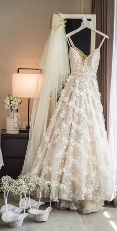 a wedding dress hanging on a rack in front of a bride's gown and shoes