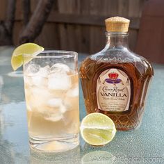 a bottle of vanilla syrup next to a glass filled with ice and lime