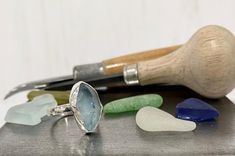 an assortment of sea glass sitting on top of a metal table next to a knife