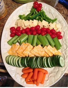 a white plate topped with cucumbers, carrots and crackers covered in cheese