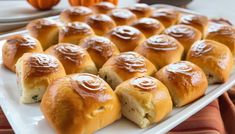 several rolls on a white platter with orange pumpkins in the backgroud