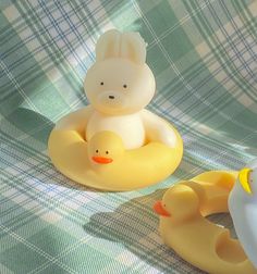 two rubber ducks sitting next to each other on a plaid cloth covered tablecloth,