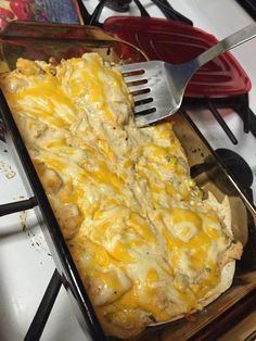 a casserole dish with chicken and cheese on it is being lifted from the oven by a spatula