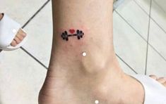 a woman's foot with a heart and barbell tattoo on her left ankle