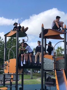 several people are sitting on the top of a play structure