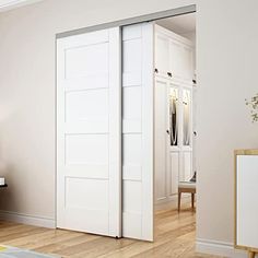 an open white door in the middle of a living room with hardwood floors and furniture