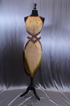 a mannequin is adorned with beaded and fringed fabric on a black stand