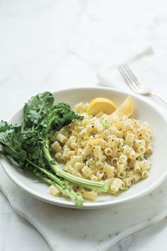 a white plate topped with macaroni and broccoli next to a fork