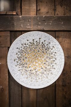 a white plate sitting on top of a wooden wall next to a light bulb in the center