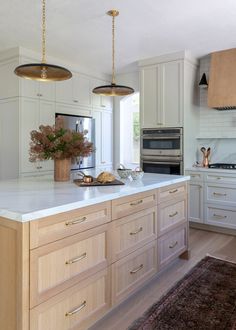 a large kitchen with white cabinets and gold accents on the counter tops, along with an area rug