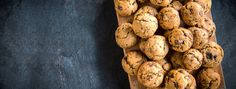 chocolate chip muffins on a wooden cutting board with black stone background, top view