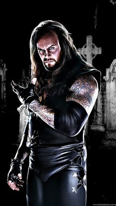 a man with long hair and tattoos wearing black leather clothes standing in front of a dark background