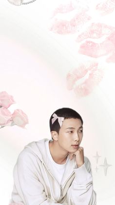 a young man sitting in front of pink flowers