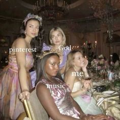 four women in dresses sitting at a table with wine glasses and candles on the table