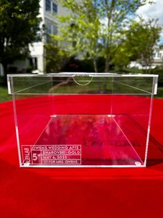 a clear acrylic box sitting on top of a red cloth covered tablecloth