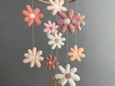 a crocheted mobile with flowers hanging from it's sides, in pastel colors