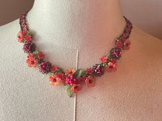 a necklace with flowers and leaves on it sitting on top of a mannequin