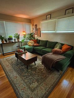 a green couch sitting on top of a wooden floor in a living room next to a coffee table