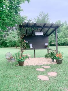 an outdoor kitchen in the middle of a grassy area with potted plants and chairs