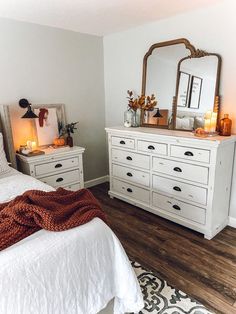 a bedroom with white furniture and candles on the nightstands, along with a large mirror