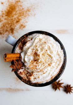 an overhead view of a cup of hot chocolate with whipped cream, cinnamon and star anise