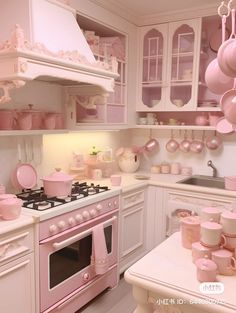 a pink and white kitchen with lots of pots and pans