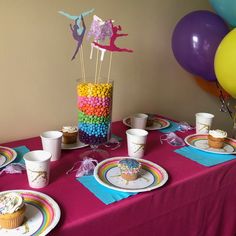 a table topped with cupcakes and cake next to balloons