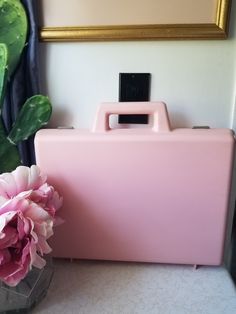 a pink case sitting on top of a table next to a vase with flowers in it