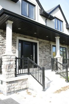 the front porch of a house with black iron railings