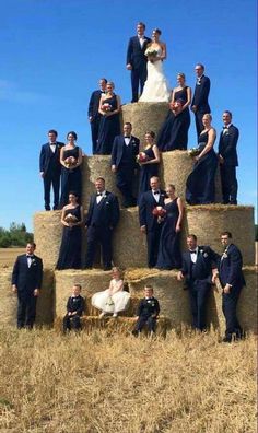 a large group of people standing on hay bales in the middle of a field