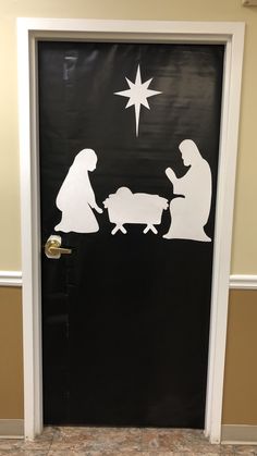 a door decorated to look like the nativity scene with silhouettes of people and baby jesus