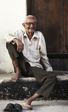 an old man sitting on the steps with his foot propped up in front of him