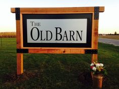 the old barn sign is next to a potted plant on the grass in front of it