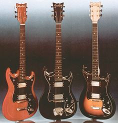 three electric guitars are lined up in a row, one is orange and the other is black