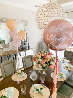 a dining room table with balloons, plates and flowers on top of it in front of a mirror that says best mom