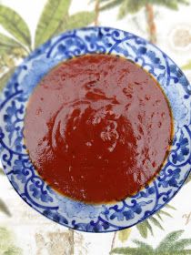 a blue and white plate filled with sauce on top of a floral tablecloth covered table