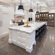 a large kitchen with white cabinets and marble counter tops, an island in the middle