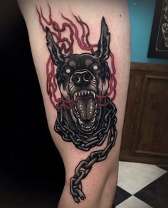 a black and red tattoo on the leg of a person with a dog's head