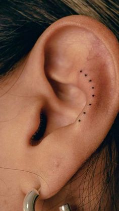 a woman's ear with small black dots on it